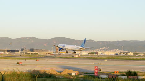 United-airlines-passenger-aeroplane-landing-at-Barcelona-airport-with-birds-flying-across-runway-field
