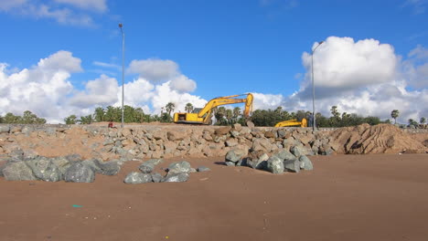 Bulldozer-creating-a-huge-wall-of-stones-near-a-beach-on-tropical-island-video-background-|-Bulldozer-machine-at-work-for-development-of-beach