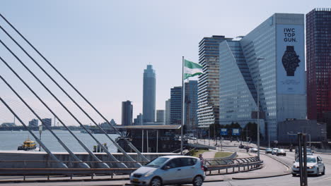 Slowmotion-shot-of-cars-driving-along-the-bridge-with-Witte-Huis-building-in-the-background,-Rotterdam-flag-flying