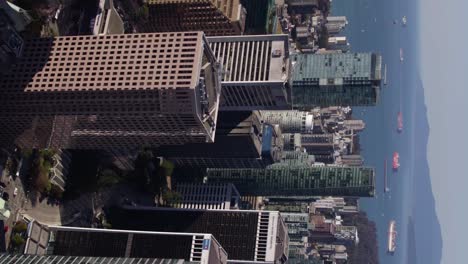 Skyscrapers-in-downtown-Vancouver,-sunny-BC,-Canada---vertical,-tracking,-drone-shot