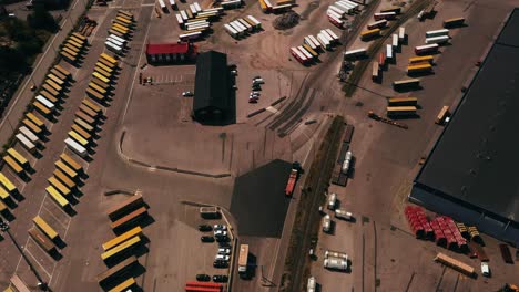 Aerial-view-overlooking-a-truck-driving-in-middle-of-cargo-at-a-shipping-terminal,-in-sunny-Finland