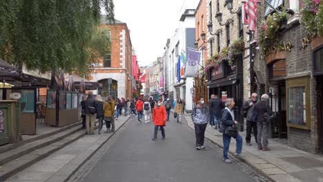 Gente-Caminando-En-La-Famosa-Calle-Temple-Bar-Con-Tiendas-En-Dublín,-Irlanda