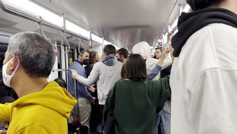 People-standing-in-busy-train-carriage-on-Milan-Metro-underground-rail