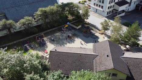 Dale-daycare-in-Dalekvam-Vaksdal-Norway---Aerial-looking-down-at-building-with-playground-and-kids-in-front