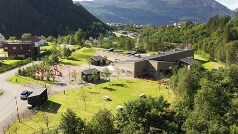 Jardín-De-Infantes-Vaksdal-En-Noruega-Vaksdal---Antena-Soleada-Con-Carretera-E16-Y-Paisaje-Montañoso-En-Segundo-Plano
