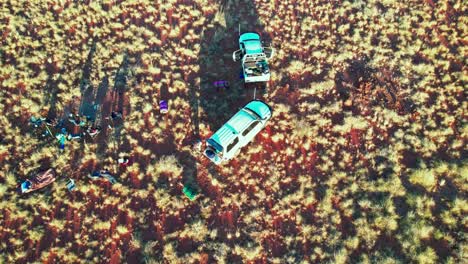 Rising-and-panning-down-drone-footage-of-a-a-group-of-campers-packing-up-their-swags-in-the-Tanami-Desert,-Northern-Territory,-Australia