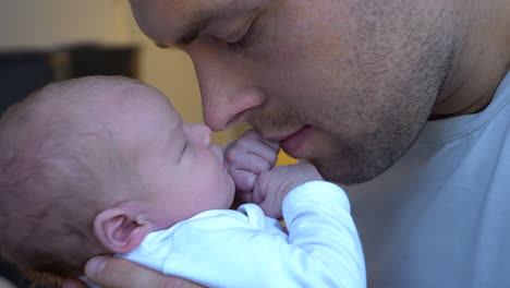 Close-up:Dad-and-Newborn-Baby-Cuddling-together-at-home---Family-in-Love-with-healthy-baby-Indoors