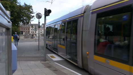 Tranvía-Con-Pasajeros-Pasando-Por-La-Parada-De-La-Estación-Heuston-En-Dublín,-Irlanda