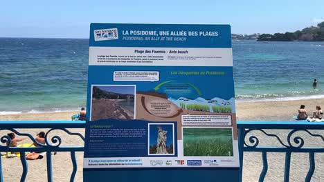 Information-Board-At-The-Beachfront-Of-Ants-Beach-With-People-Swimming-In-The-Background