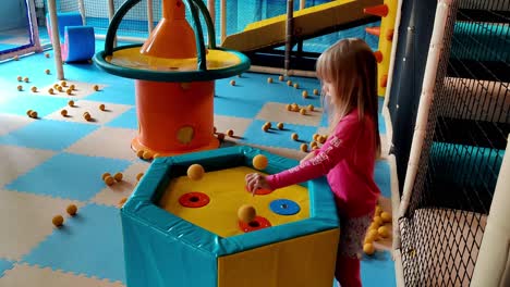 Cute-6-year-old-blonde-girl-in-pink-clothes-playing-and-learning-science-with-flying-foam-balls-at-indoor-playground-in-Voss-Norway---Handheld-static