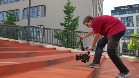 Man-Holding-Gimbal-and-Camera,-Walking-on-Stairs-and-Shooting-Low-Angle-City-Footage