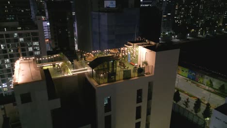 Drone-shot-of-a-hotel-with-a-rooftop-garden-in-Seoul-at-night,-South-Korea