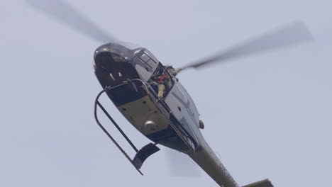 Helicóptero-Militar-Con-Soldado-Sosteniendo-Rifle-De-Francotirador-Volando-En-El-Cielo,-ángulo-Bajo