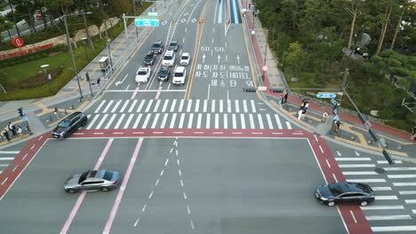 Peatones-Y-Automóviles-Esperando-Y-Cruzando-Una-Intersección-Cerca-De-Lotte-World-Tower,-Seúl,-Corea-Del-Sur