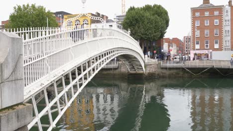 People-Cross-At-The-Ha'penny-Arch-Bridge-Over-Liffey-River-In-Dublin-City,-Ireland