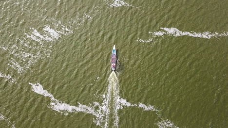 Drone-view-from-above-of-a-blue-boat-sailing-through-turquoise-green-waters