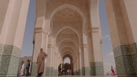 Marokkanischer-Mann-In-Traditioneller-Kleidung,-Der-Ehrfürchtig-Auf-Hufeisenstilbögen-In-Der-Hassan-ii-moschee-In-Casablanca-Blickt
