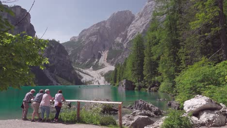 People-leaning-on-a-wooden-fence,-enjoying-the-beautiful-view-of-lake-Braies