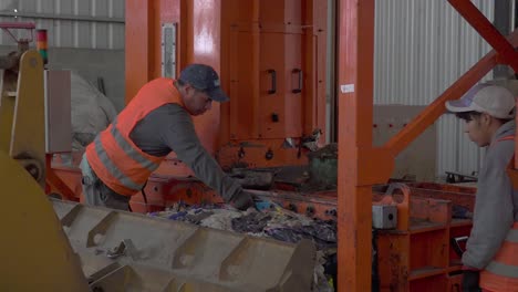 Zwei-Arbeiter-Laden-Verdichteten-Müll-Auf-Einen-Bulldozer-In-Einer-Abfallverarbeitungsanlage