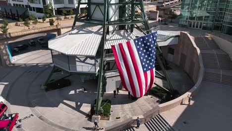 Aerial-view-of-people-raising-the-US-flag-to-a-tower-on-Independence-day-in-USA---orbit,-drone-shot