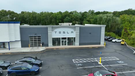 Rising-aerial-of-Tesla-dealership,-showroom-and-repair-maintenance-center-for-electric-cars