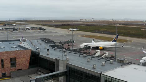 Keflavíkurflugvöllur-airport-building-with-Boeing-airplane-parked-at-gate,-aerial