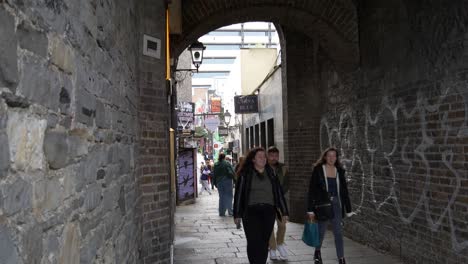 Gente-Caminando-En-La-Entrada-Del-Arco-De-Comerciantes-Que-Conduce-A-La-Calle-Temple-Bar-En-Dublín,-Irlanda