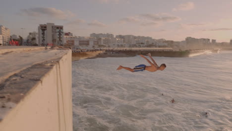 Young-arabic-man-diving-head-first-into-the-Atlantic-Ocean-waters-at-sunset-near-Hassan-II-mosque-in-Casablanca-Morocco