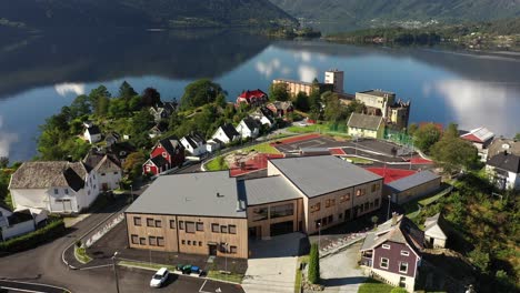 Neue-Moderne-Grundschule-In-Atemberaubender-Lage-Mit-Fjord-Im-Hintergrund-Und-Grüner-Waldlandschaft-Drumherum---Sich-Vorwärts-Bewegende-Antenne-über-Dem-Gebäude-Und-In-Richtung-Spielplatz---Vaksdal-Norwegen