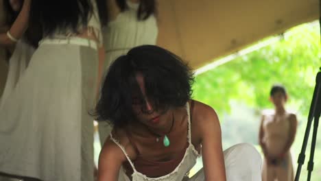 Asian-woman-dressed-in-organic-white-cotton-dress-swaying-in-circular-movement-at-ecstatic-dance-performance,-filmed-in-slow-motion-and-medium-shot