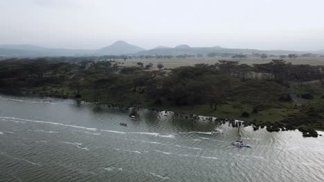 View-of-drone-flying-away-from-three-ships-navigating-Lake-Naivasha,-Kenya,-Africa