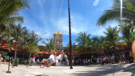 Mayan-people-performing-ritual-of-"Danza-de-los-Voladores"-|-landing-on-ground-attached-with-ropes-from-high-pole-|-Tourists-watching-Danza-de-los-Voladores-performance-in-Costa-Maya-port
