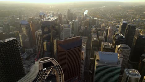 Aerial-view-overlooking-rooftops-of-skyscrapers-in-downtown-of-Calgary,-golden-hour-in-Alberta,-Canada---pan,-drone-shot