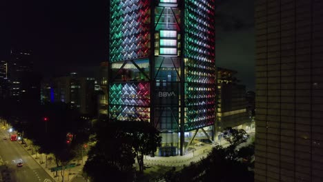 Aerial-view-in-front-of-BBVA-tower-illuminated-in-the-colors-of-the-Mexican-flag,-Independence-day-in-Mexico-city
