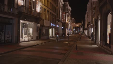 Vista-Estática-De-Ciclistas-Conduciendo-Por-El-Distrito-Comercial-De-Gante,-Bélgica-Por-La-Noche