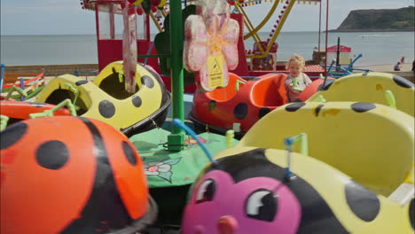 Toddler-on-a-ladybird-carousel-ride-at-a-seaside-amusement-park-in-Scarborough-UK