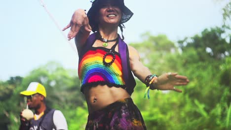 Asian-woman-dressed-in-rainbow-pattern-top-moving-arms-in-unique-ecstatic-dance,-filmed-in-slow-motion-as-medium-tight-shot