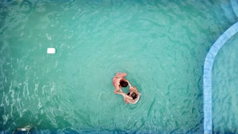 Drone-view-from-above-of-a-group-of-girls-playing-while-swimming-in-a-pool