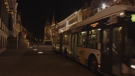 Bus-driving-through-historical-city-center-in-Ghent,-Belgium-at-night