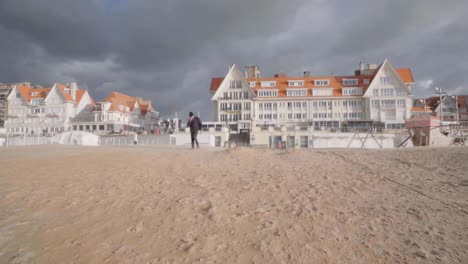 Senior-man-walking-on-the-beach-of-coastal-village-De-Haan-in-Belgium-during-windy-autumn-day