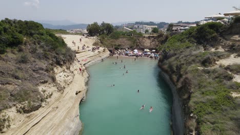 Aerial-flyover-of-the-Corfu-Canal-d'Amour-in-Greece,-people-sunbathe-and-swim-in-Channel-of-Love