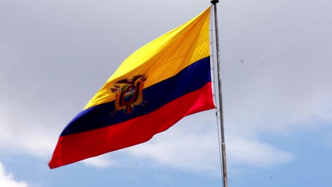 Ecuador-flag-is-waving-with-steel-pool-against-blue-cloudy-sky-in-quito-capital-city-of-the-country-4k