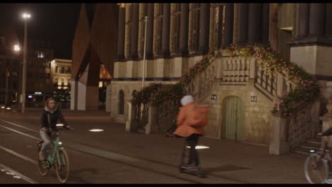 Leute-Auf-Fahrrädern-Fahren-Nachts-Durch-Das-Historische-Stadtzentrum-Von-Gent,-Belgien,-Während-Ein-Geiger-Musik-Spielt