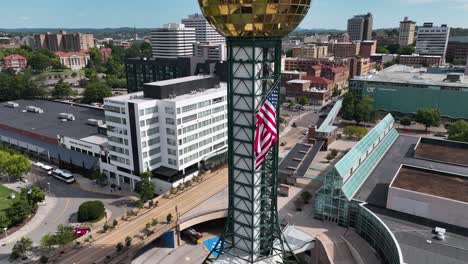 Aerial-view-away-from-the-US-flag-on-the-Sunsphere-tower-in-USA---rotating,-reverse,-drone-shot