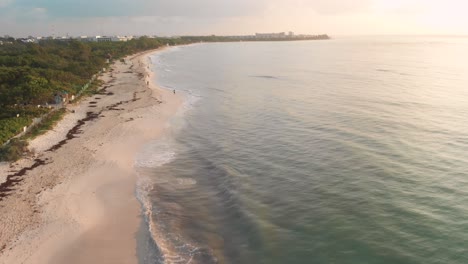 Cinematic-drone-shot-flying-over-shoreline-of-Playa-publica-in-the-Mexican-coastal-town-of-Playa-del-Carmen,-Quintana-Roo