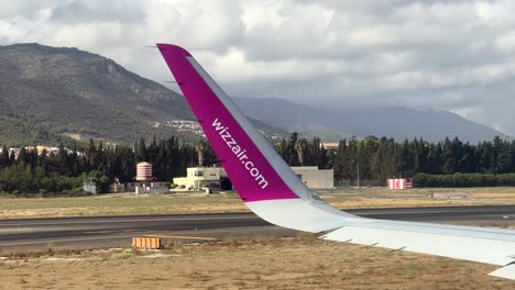 Close-up-plane-wing-with-Wizz-Air-logo-taxiing-on-airport-tarmac