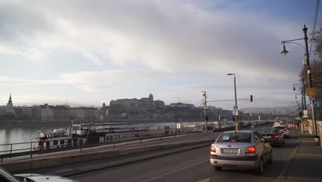 Traffic-in-Budapest-street,-Buda-Castle-in-background,-panning-left-view,-Hungary