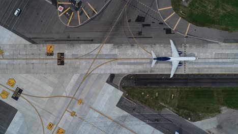 Aerial-view-above-a-plane-taxiing-towards-the-runway---birds-eye,-drone-shot