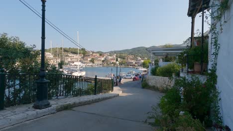 View-of-anchored-sailboats-in-the-marina,-tourists-on-the-coast-in-Kassiopi,-Corfu,-Greece