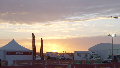Blick-Auf-Das-Biwak-Der-Dakar-rallye-Bei-Sonnenuntergang-Mit-Einem-Hubschrauber,-Der-Den-Himmel-überquert